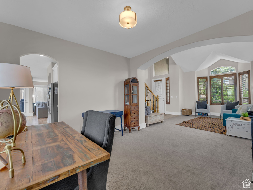 Home office with arched walkways, light colored carpet, and baseboards