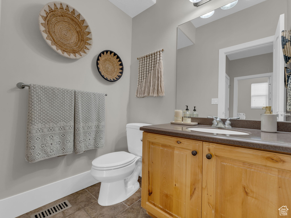 Bathroom featuring toilet, tile patterned flooring, and vanity