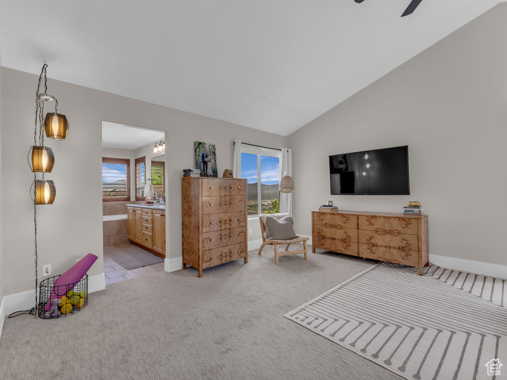 Bedroom featuring light colored carpet, baseboards, vaulted ceiling, ensuite bathroom, and a ceiling fan