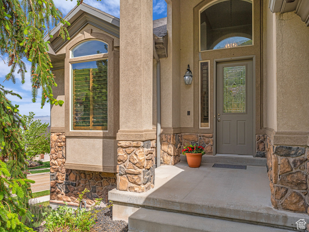 Entrance to property with stone siding, stucco siding, and a porch