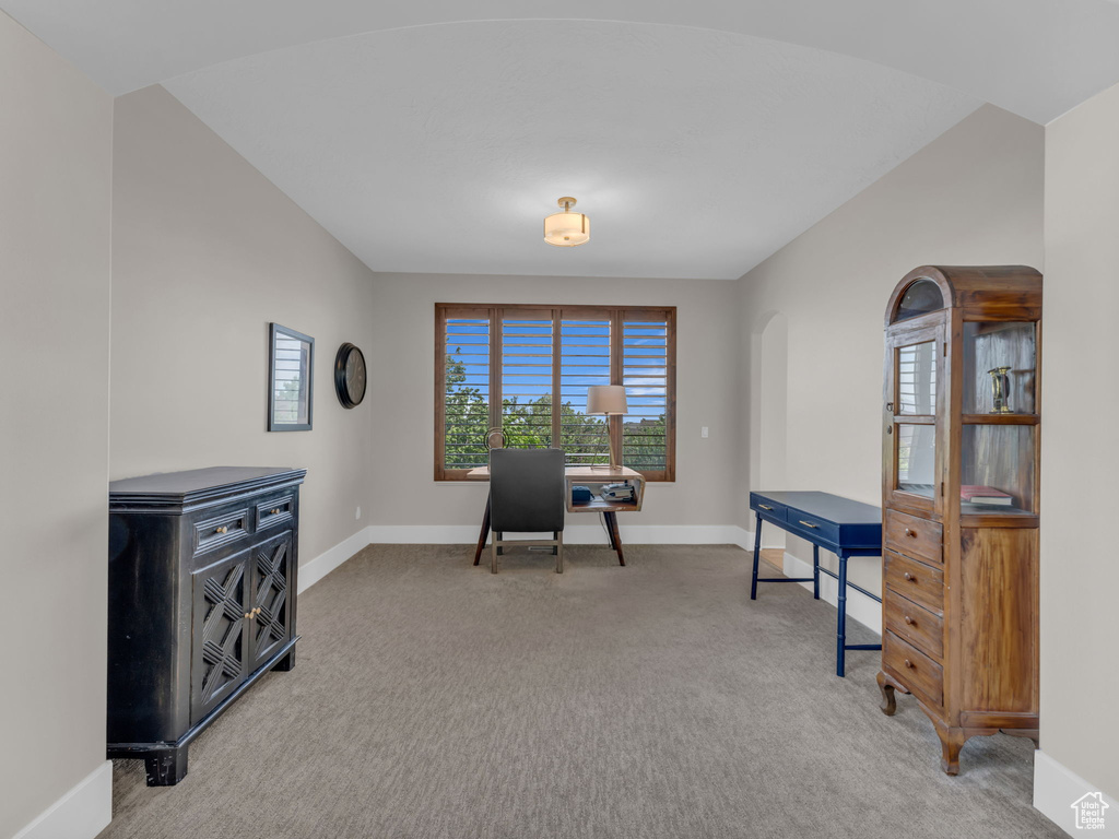 Carpeted office space featuring baseboards and arched walkways
