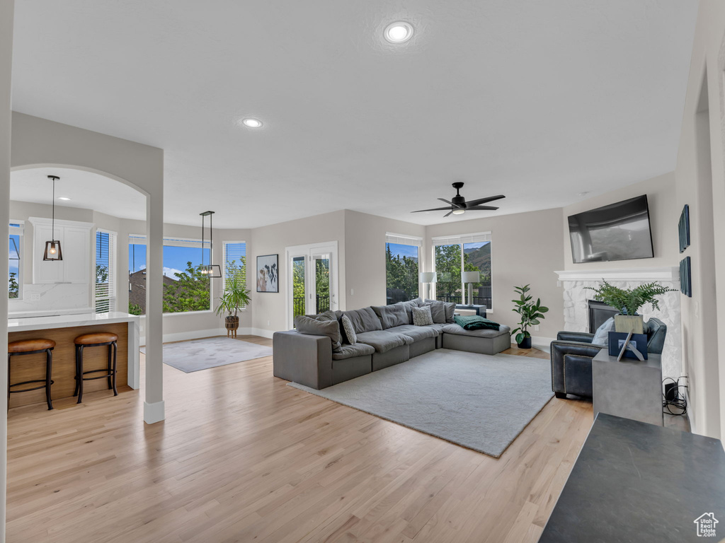 Living room with light wood-type flooring, baseboards, a ceiling fan, recessed lighting, and a fireplace
