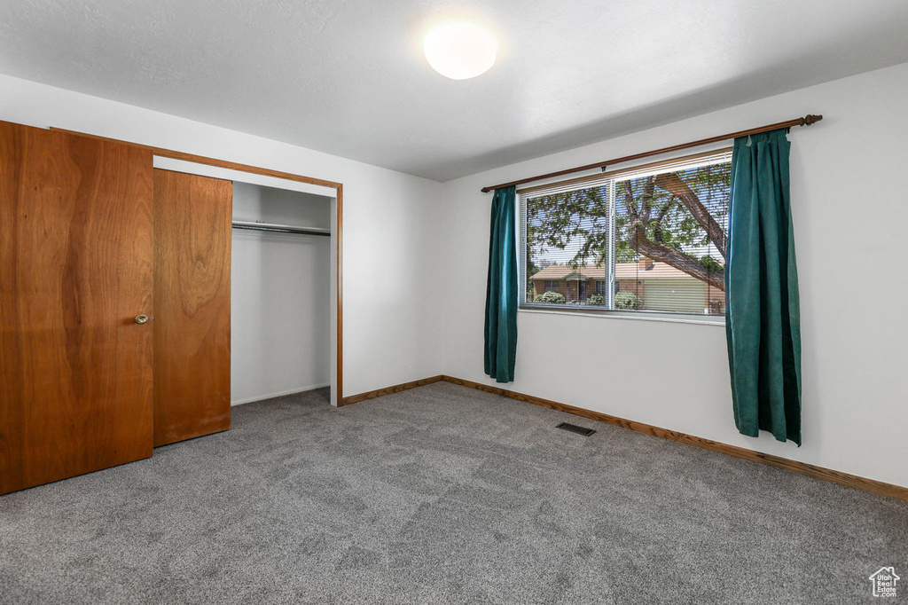 Unfurnished bedroom with carpet floors, a closet, and baseboards