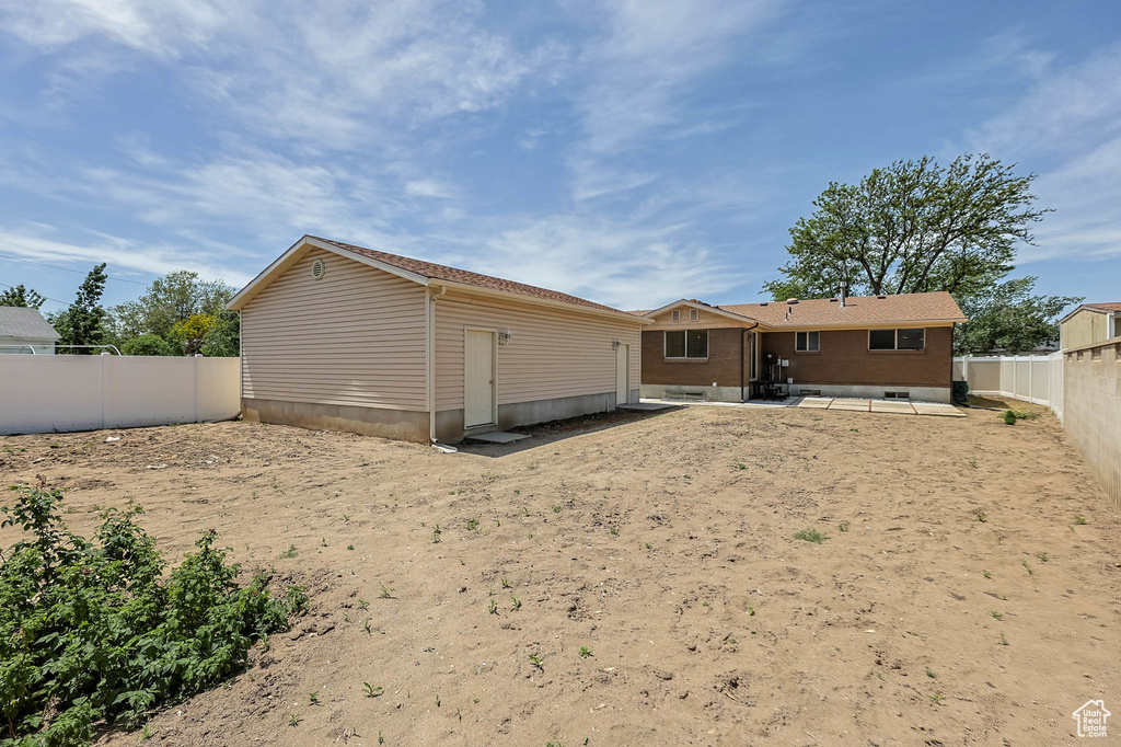 Back of property with a patio area, a fenced backyard, an outbuilding, and brick siding