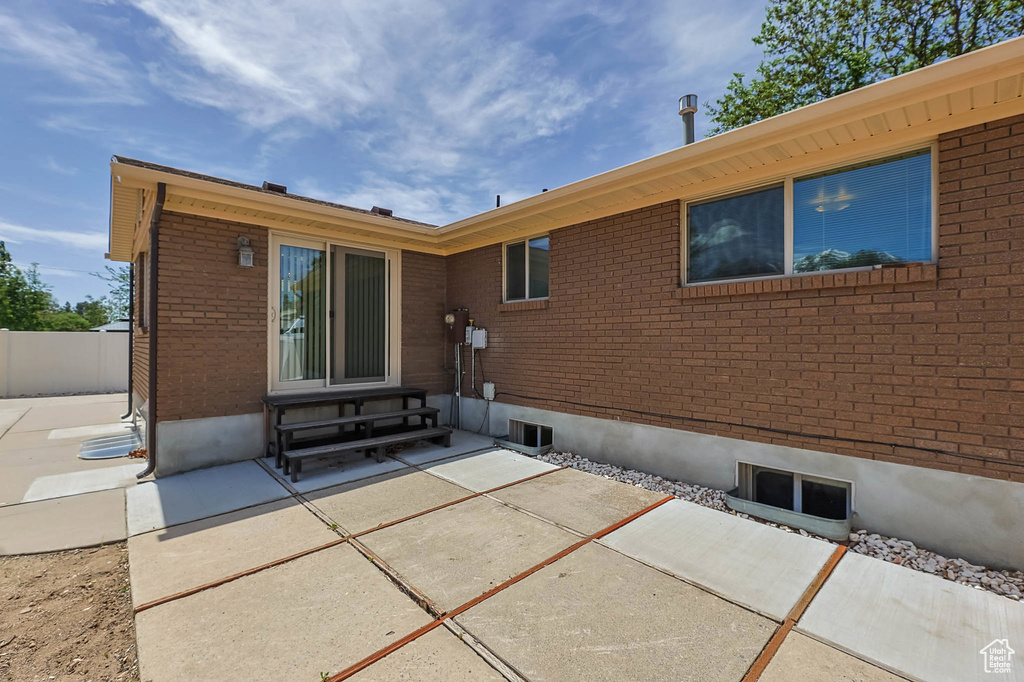 Back of property featuring entry steps, a patio area, brick siding, and fence