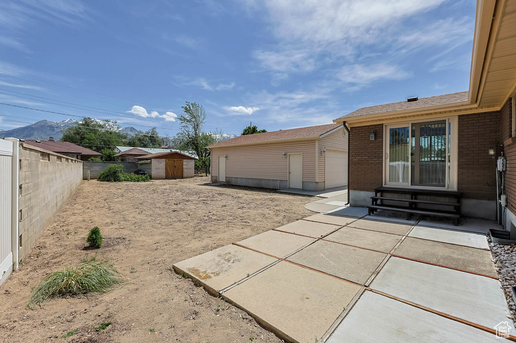 Fenced backyard featuring entry steps, a storage shed, a patio, and an outdoor structure