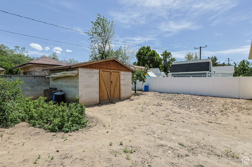View of yard with a shed, fence, and an outdoor structure