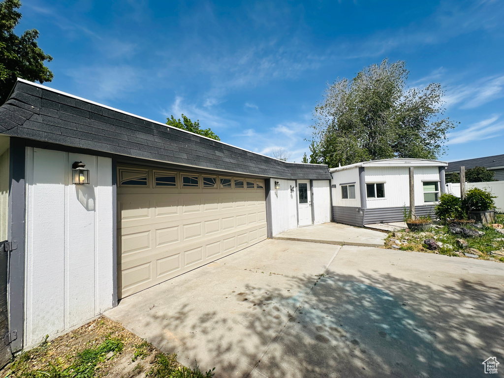 View of front of property featuring driveway, an attached garage, and roof with shingles