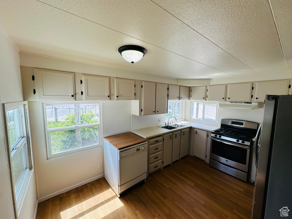Kitchen with stainless steel appliances, a sink, dark wood-type flooring, light countertops, and a textured ceiling