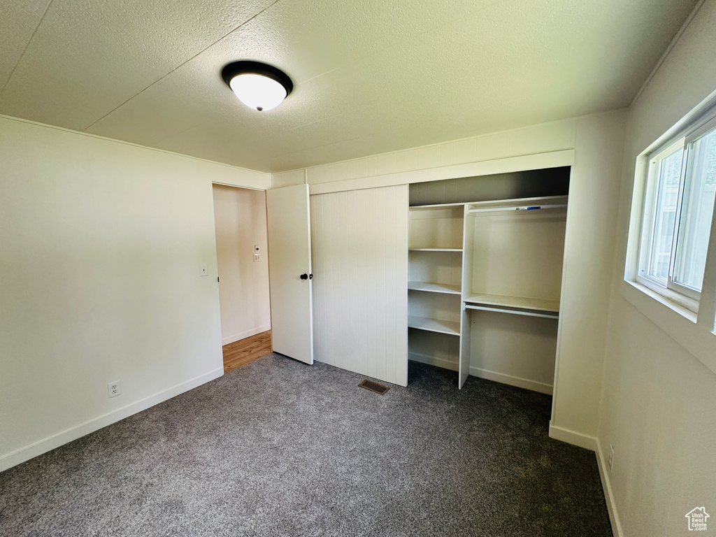 Unfurnished bedroom with carpet flooring, a closet, baseboards, and a textured ceiling