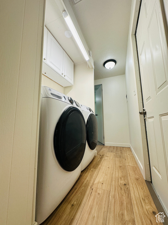 Laundry room with cabinet space, light wood finished floors, washer and dryer, and baseboards