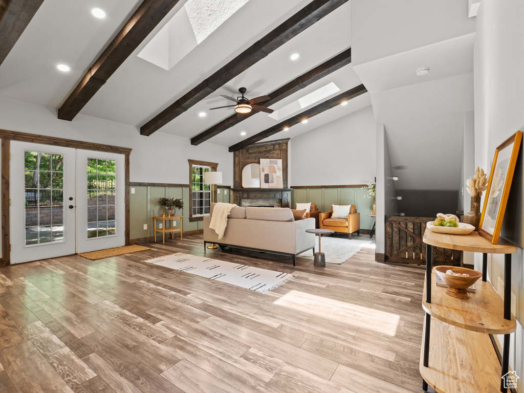 Living room featuring a skylight, wood finished floors, french doors, a ceiling fan, and recessed lighting