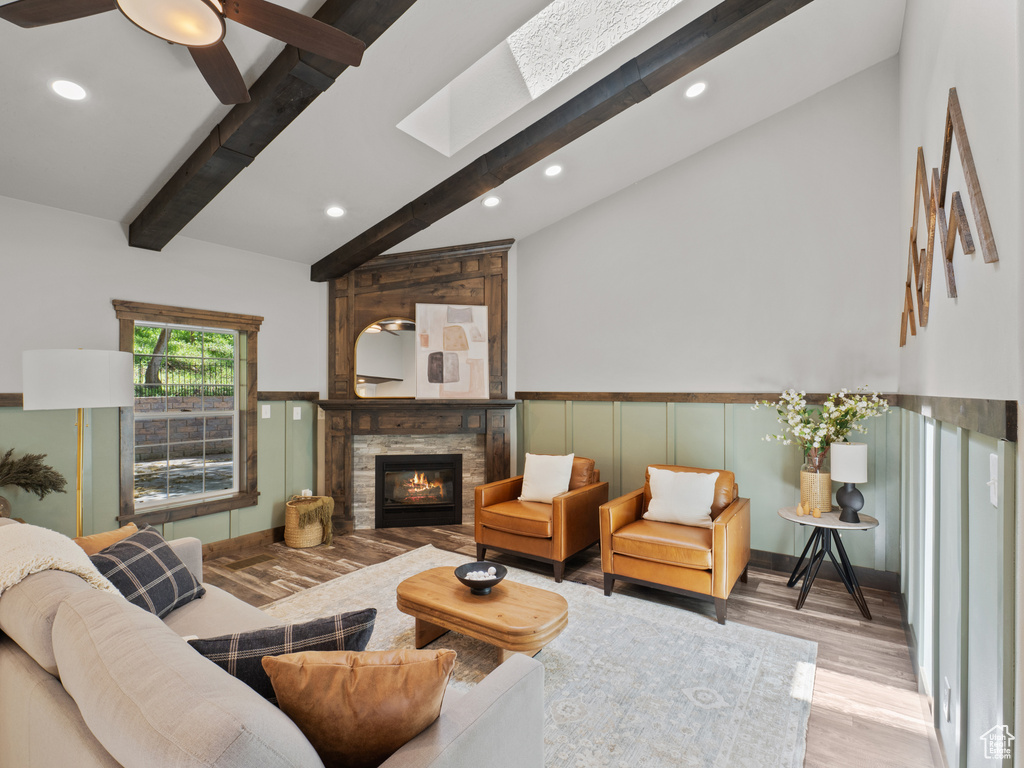 Living room with wood finished floors, recessed lighting, a fireplace, wainscoting, and ceiling fan
