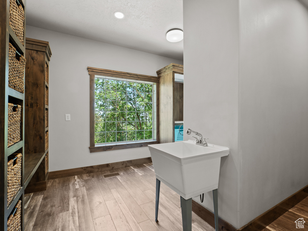 Clothes washing area featuring baseboards and wood finished floors