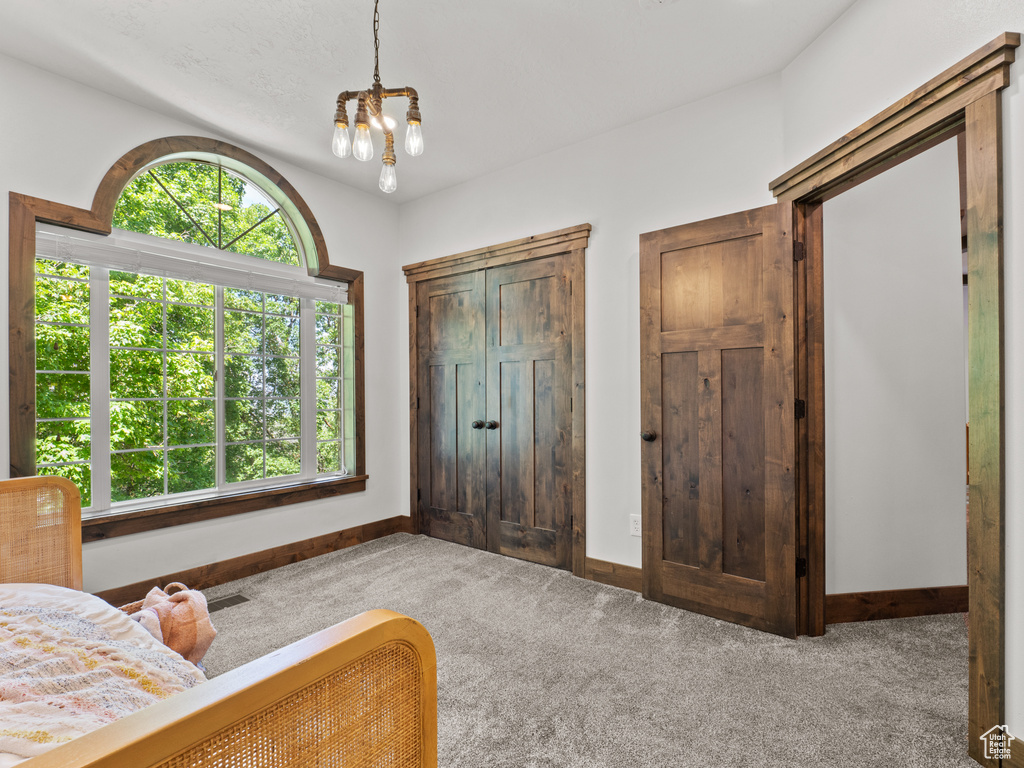 Bedroom featuring carpet floors, a chandelier, and baseboards