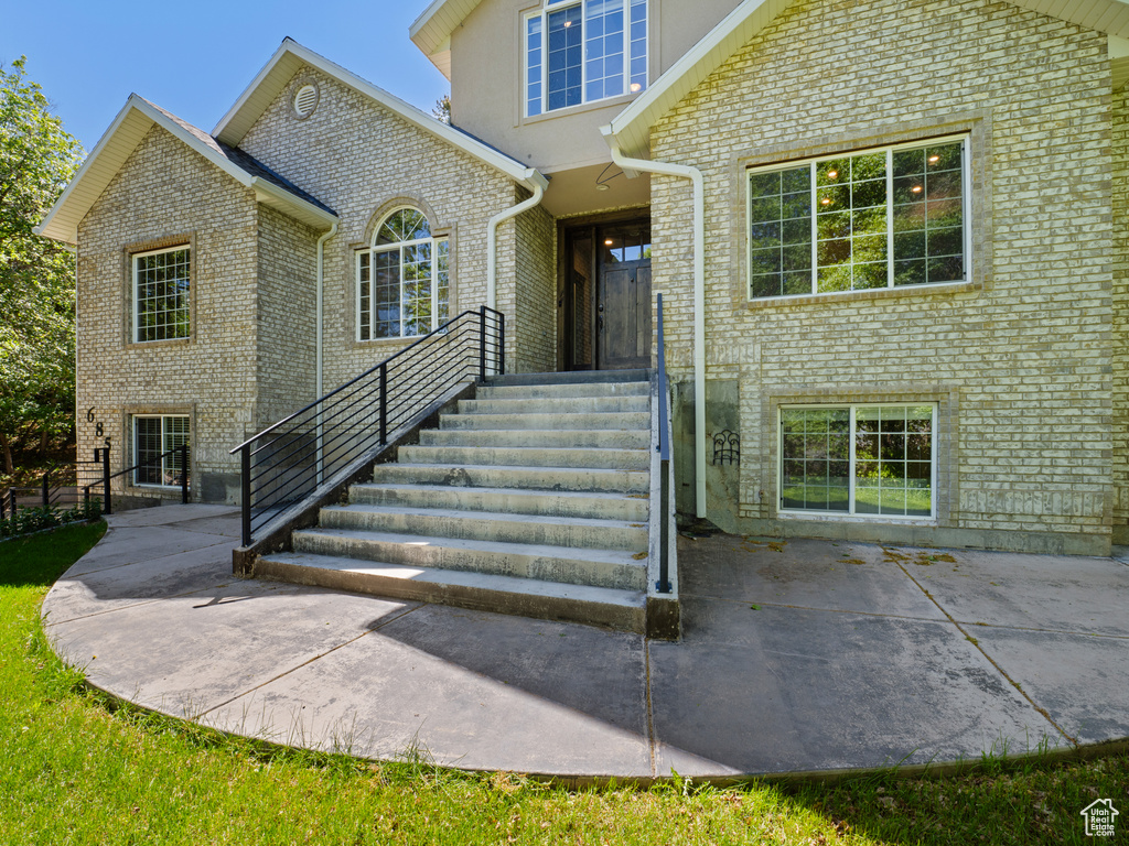 Doorway to property featuring brick siding and a patio