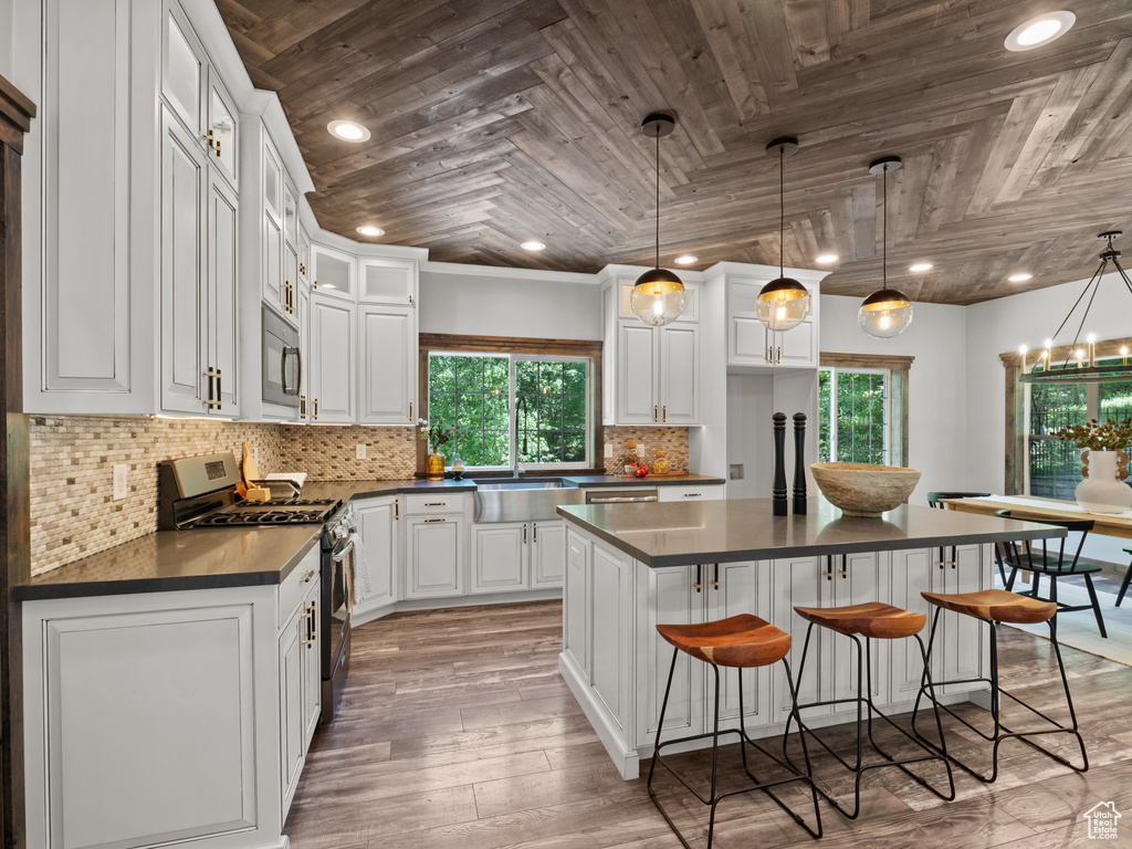 Kitchen featuring gas range, wooden ceiling, dark countertops, black microwave, and a sink