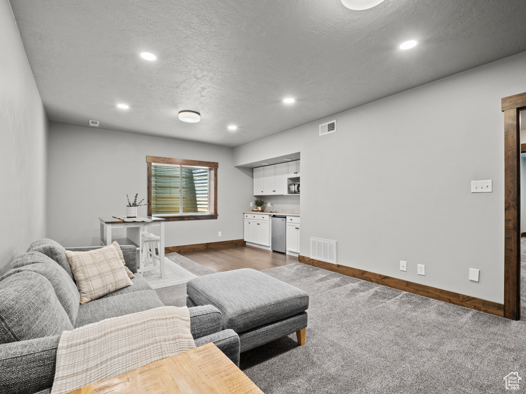 Living room with baseboards, recessed lighting, a textured ceiling, and bar area