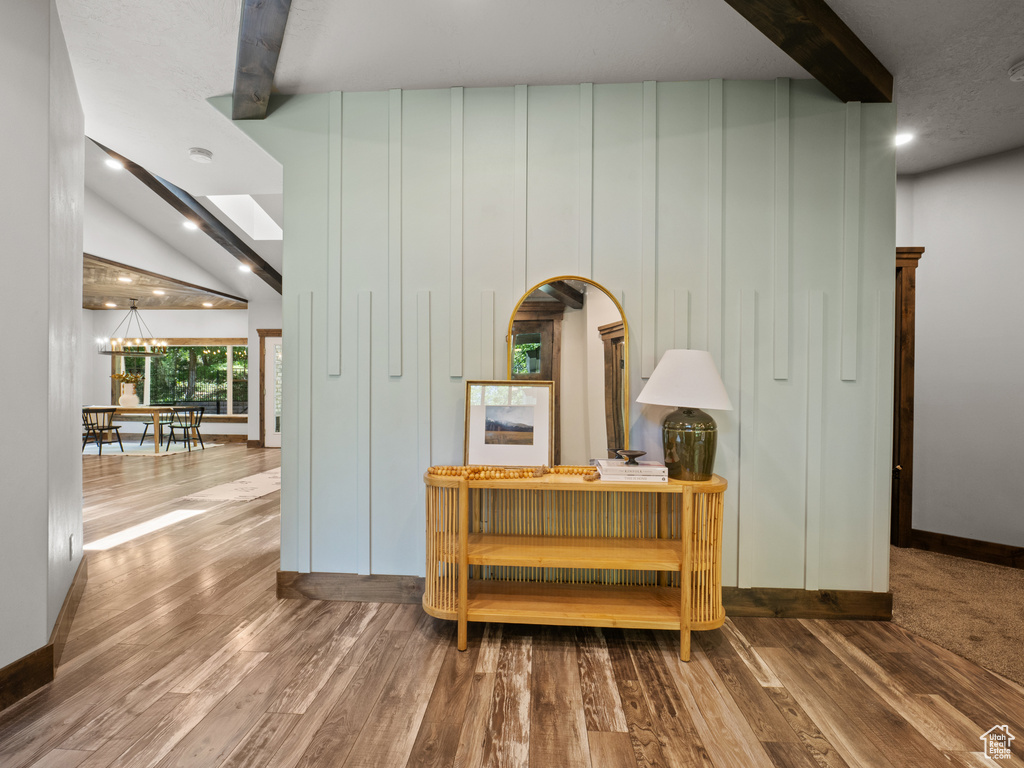 Hallway featuring wood finished floors, a chandelier, and baseboards