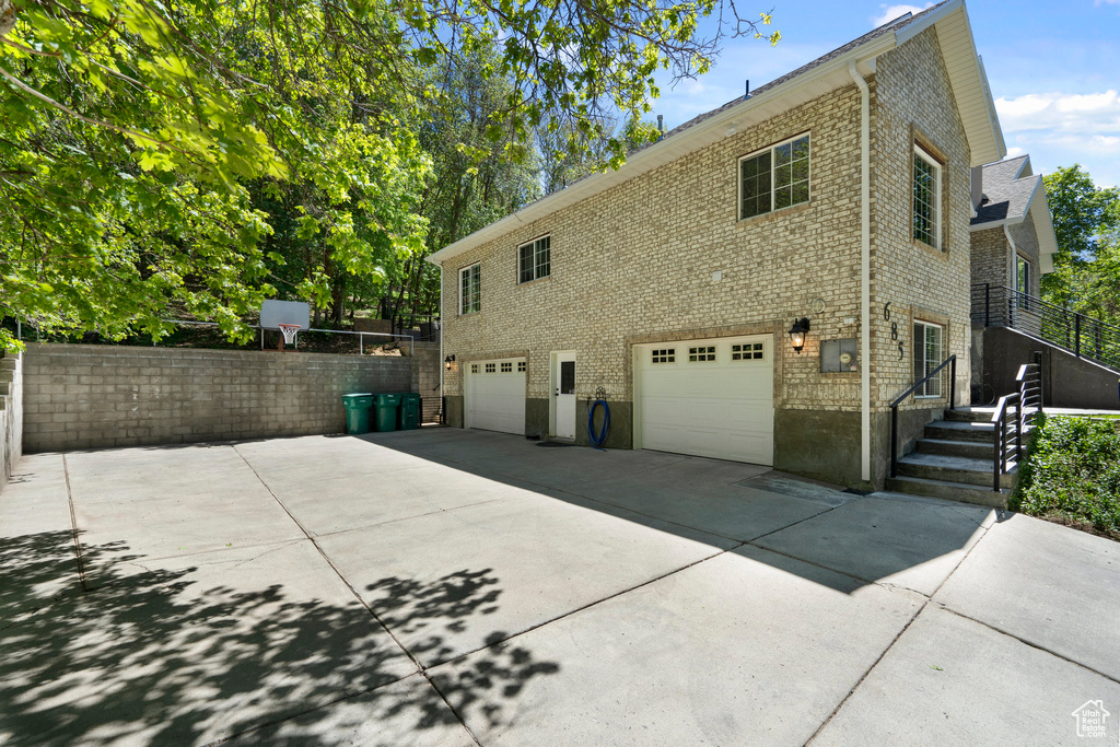 View of property exterior with a garage, concrete driveway, and brick siding