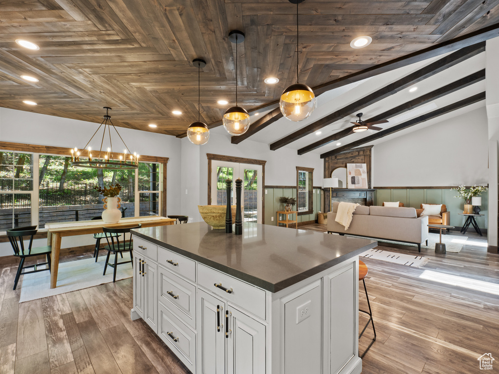 Kitchen with dark countertops, a kitchen island, white cabinetry, recessed lighting, and decorative light fixtures