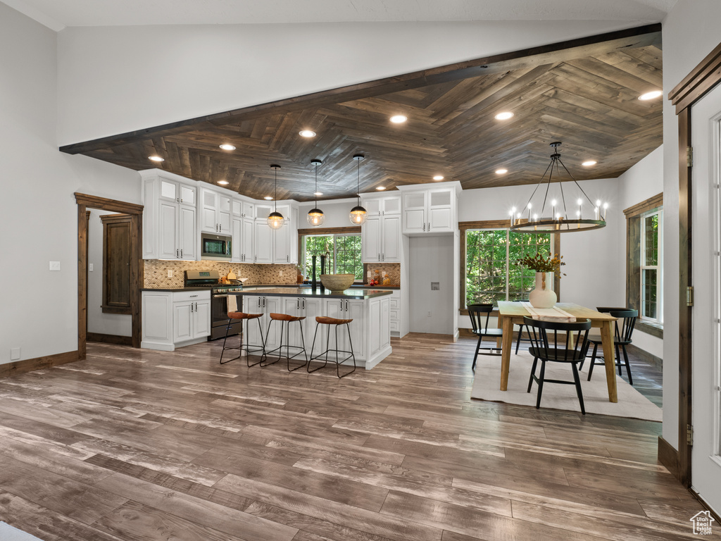 Kitchen with stainless steel appliances, dark countertops, white cabinets, glass insert cabinets, and tasteful backsplash