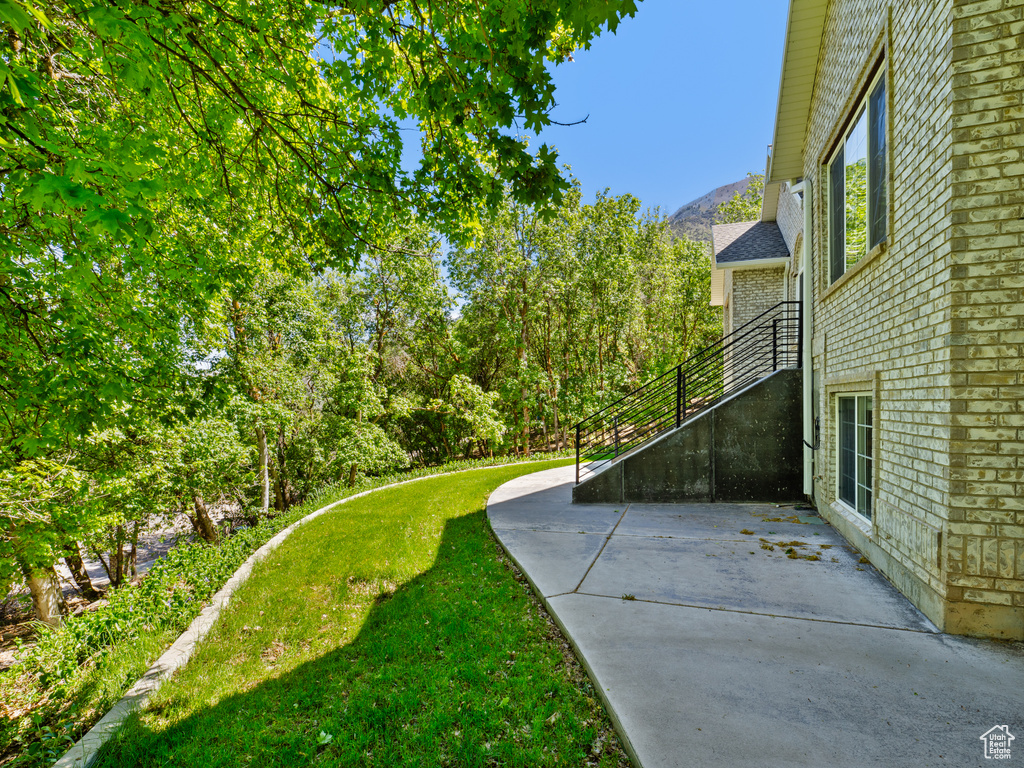 View of green lawn featuring a patio and a mountain view