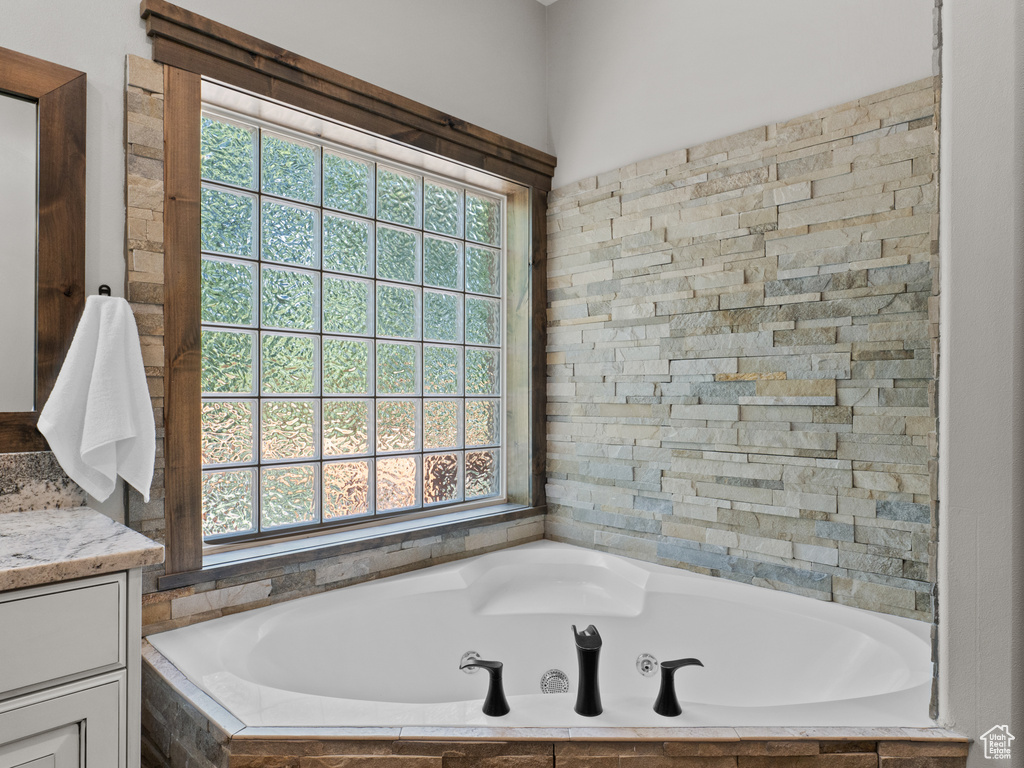 Full bathroom with healthy amount of natural light, a bath, and vanity