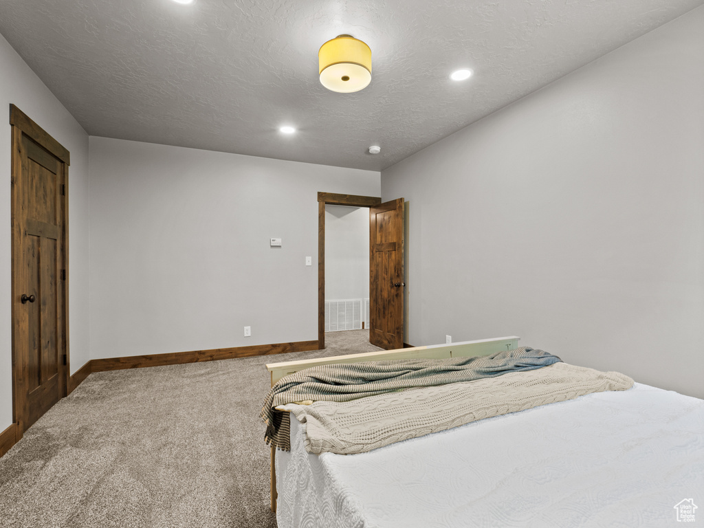 Carpeted bedroom featuring baseboards, recessed lighting, and a textured ceiling