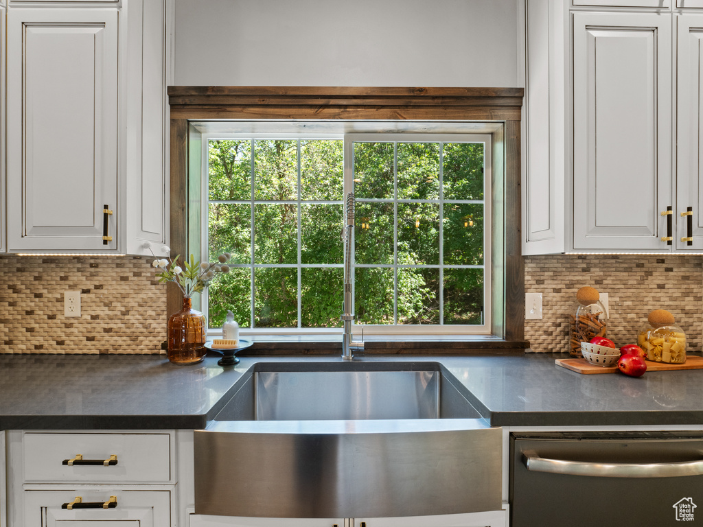 Kitchen featuring dishwasher, dark countertops, and decorative backsplash