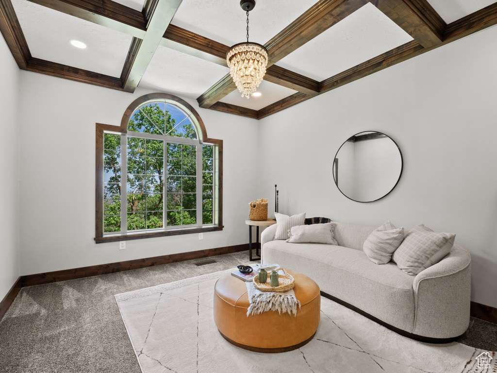 Carpeted living area with coffered ceiling, a chandelier, baseboards, and beam ceiling