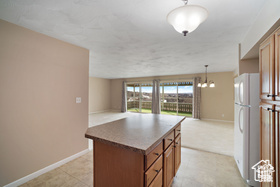 Kitchen with freestanding refrigerator, open floor plan, brown cabinets, and baseboards
