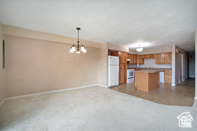 Kitchen with freestanding refrigerator, baseboards, open floor plan, stove, and a kitchen island
