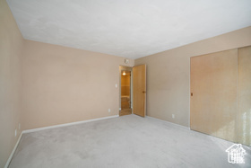 Empty room featuring light colored carpet and baseboards