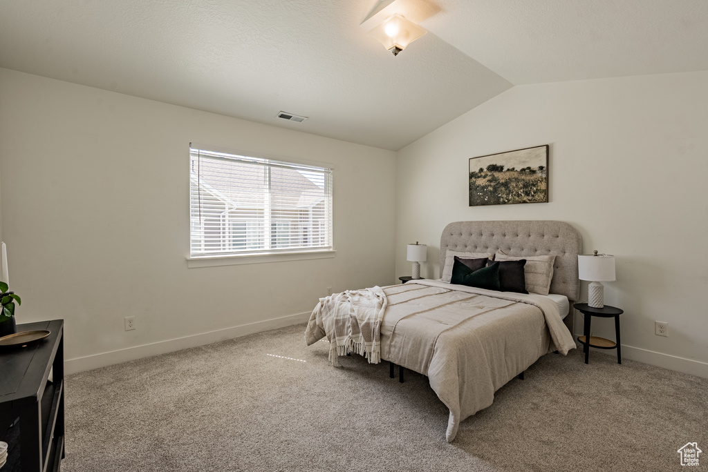 Bedroom with vaulted ceiling, baseboards, and carpet floors