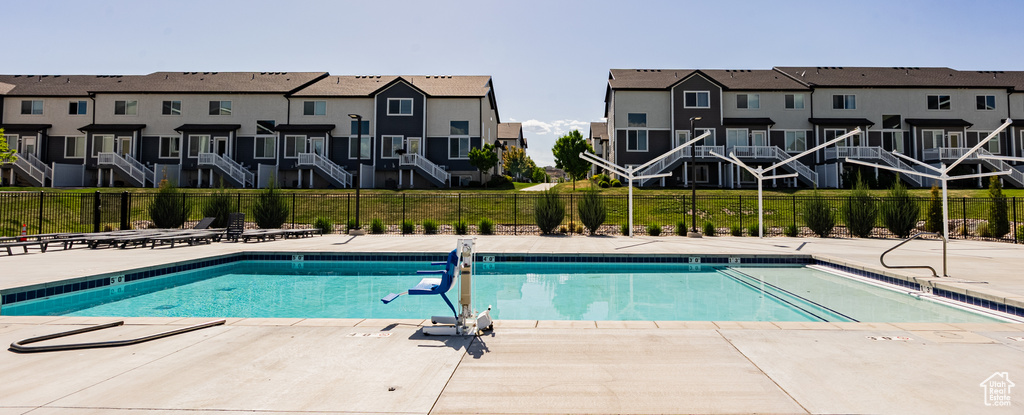 Community pool with fence, a residential view, and a patio