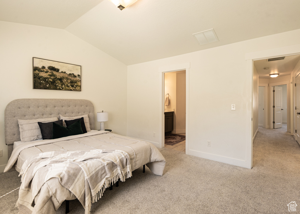Bedroom with vaulted ceiling, light carpet, baseboards, and connected bathroom