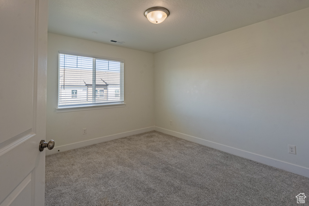 Carpeted spare room featuring baseboards