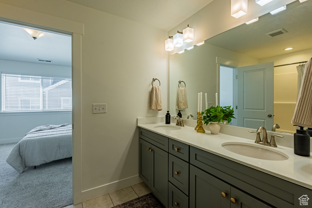 Bathroom featuring tile patterned flooring, baseboards, double vanity, and connected bathroom
