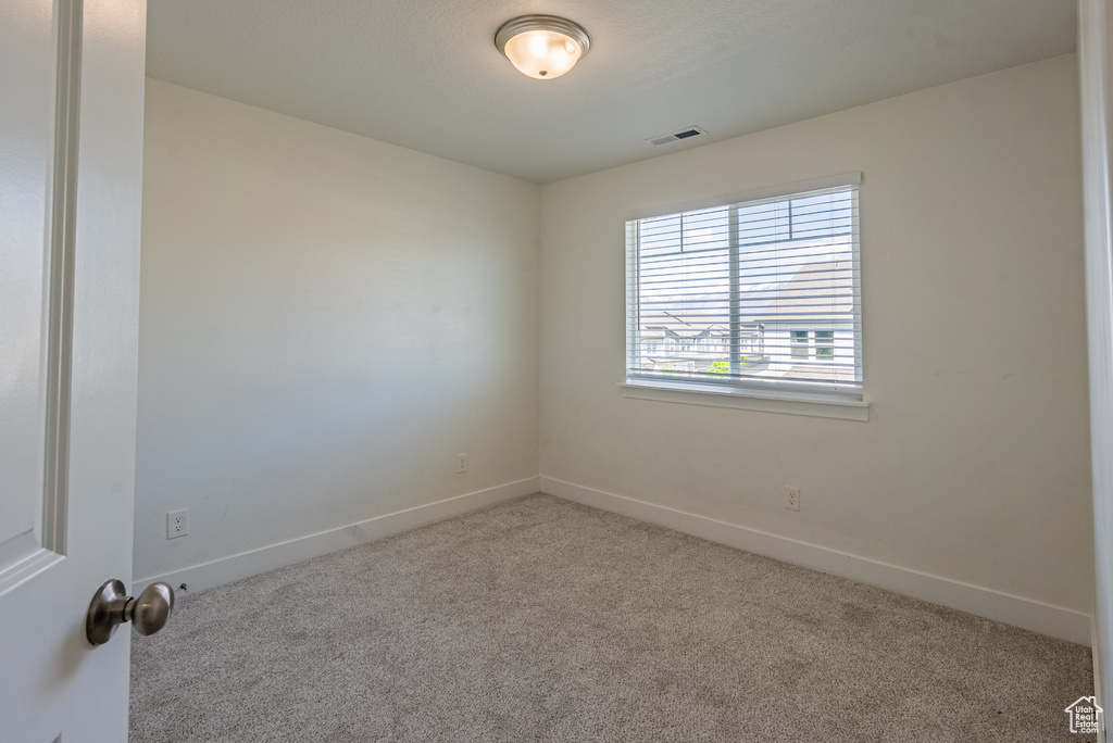 Spare room featuring carpet flooring and baseboards