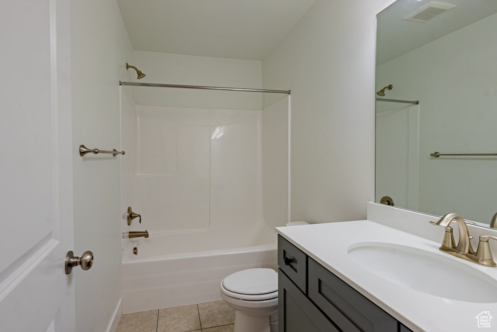 Full bath with tile patterned flooring, toilet, vanity, and shower / tub combination