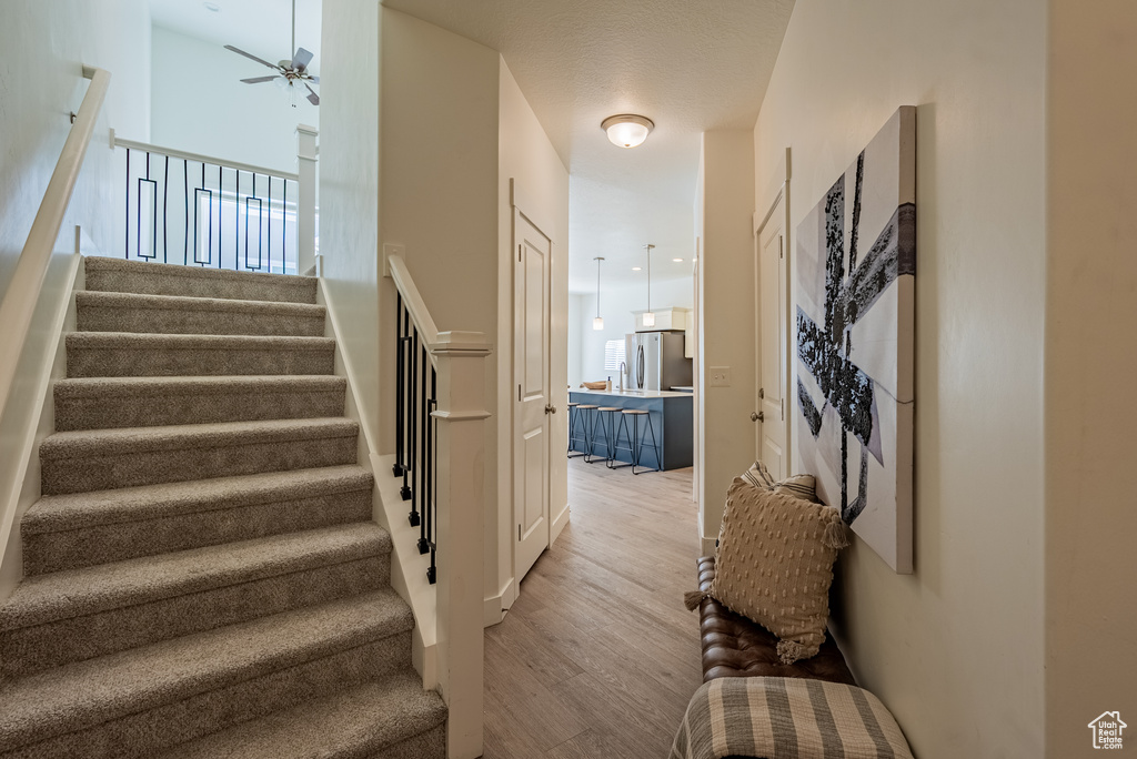 Stairs featuring wood finished floors and a ceiling fan