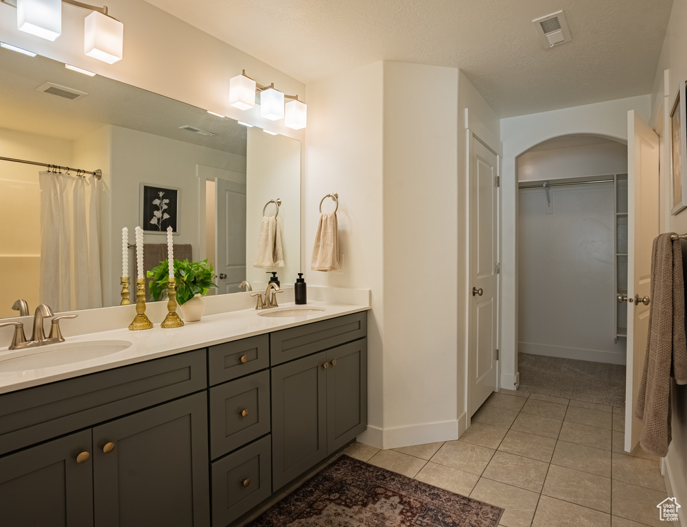 Full bath with tile patterned flooring, double vanity, baseboards, and a spacious closet