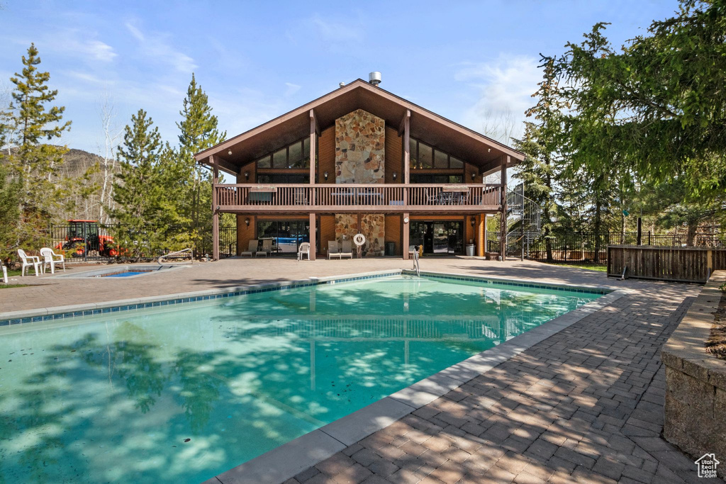 Community pool featuring a patio area, a hot tub, and fence