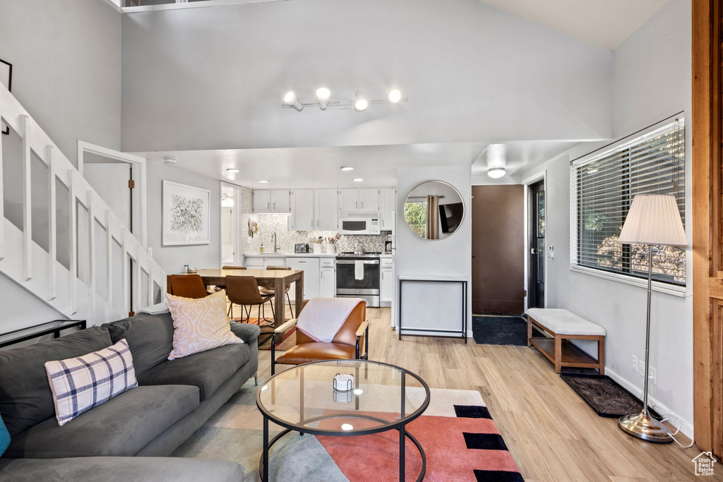Living area featuring light wood-style floors, stairway, and baseboards