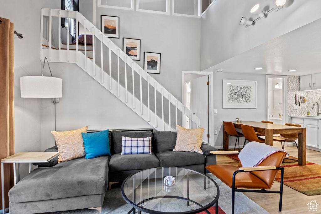 Living area with light wood-style flooring, stairs, a high ceiling, and recessed lighting