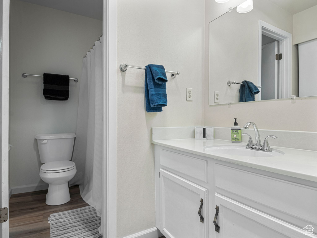 Full bathroom featuring baseboards, toilet, vanity, and wood finished floors