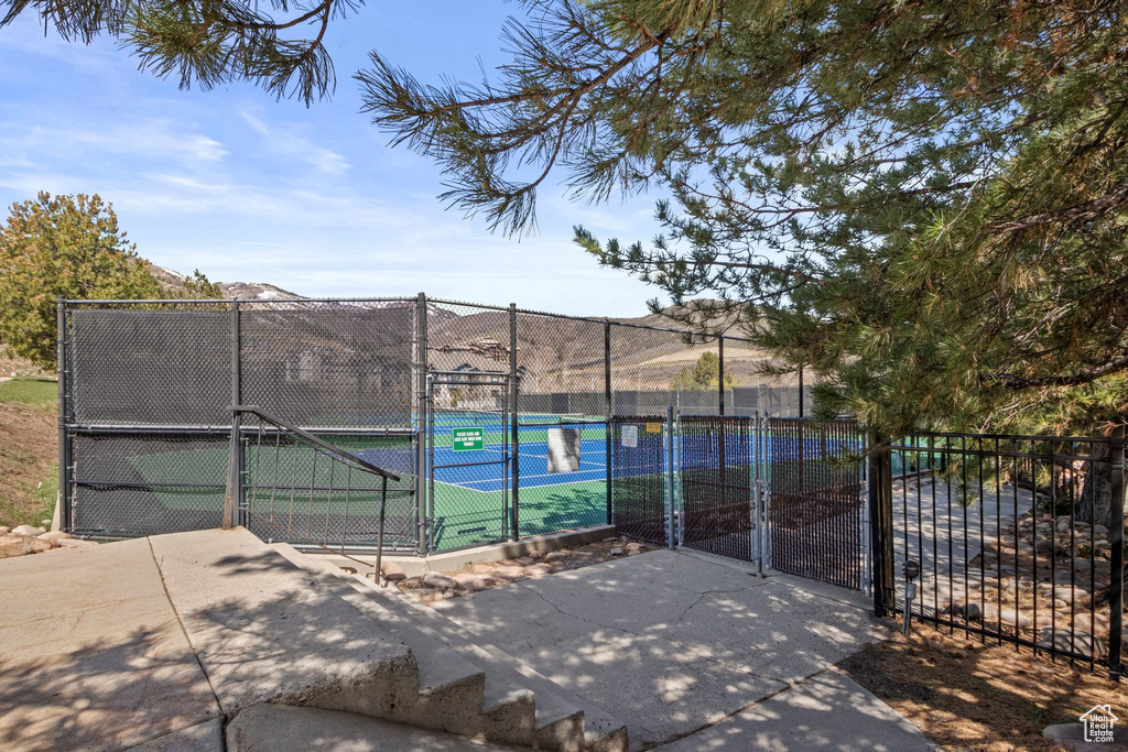 View of tennis court featuring a gate and fence