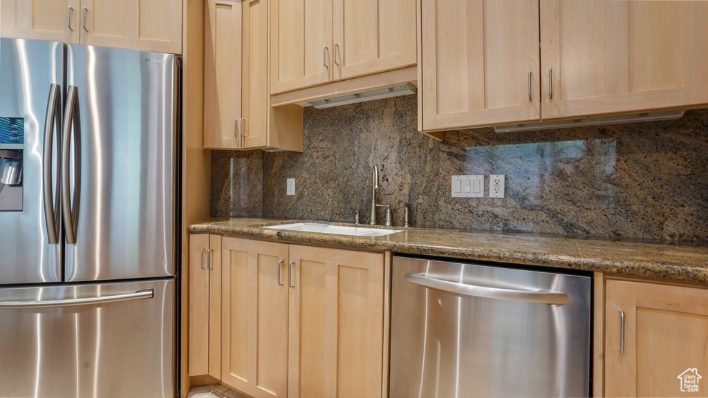 Kitchen with appliances with stainless steel finishes, light brown cabinetry, and a sink