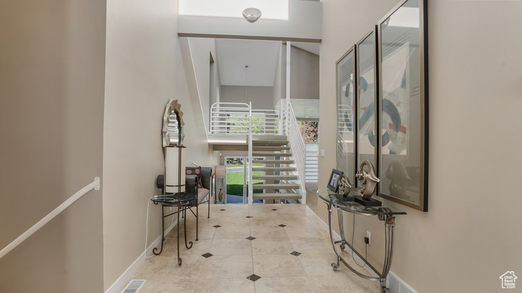 Corridor with a towering ceiling, baseboards, and tile patterned floors